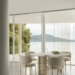 Turri, marchio italiano sinonimo di artigianalità, su misura e stile sofisticato, dà vita ad una nuova narrazione, attraverso uno shooting raffinato, primo passo di un rinnovato progetto di comunicazione. Ambientate in una villa a bordo d’acqua, circondata da una natura rigogliosa, le immagini, realizzate da Andrea Papini e curate nello styling da Studio Salaris, mettono in risalto la collezione Atelier disegnata da Matteo Nunziati. La collezione si integra armoniosamente in questo ambiente sereno ed esclusivo, riflettendo perfettamente il savoir-faire italiano per eccellenza che Turri incarna. La villa, che ospita le più recenti collezioni dell’azienda, è una testimonianza di eleganza moderna e raffinatezza architettonica. La struttura leggera è definita da una facciata intricata, dove gruppi di sottili aste metalliche creano un motivo ritmico e irregolare. Gli elementi formano un sottile schermo tra l'interno e il paesaggio circostante, evocando l'immagine ipnotica di gocce d'acqua che scendono a cascata dai piani orizzontali sospesi. Questa interazione tra architettura e natura rispecchia l'etica della collezione di mobili, dove ogni pezzo è realizzato con cura per fondere bellezza, comfort e grazia senza tempo. Turri ha realizzato, per la prima volta, anche un video emozionale girato da MOFO Milano, che racconta la location e le collezioni presentate. Accanto agli ambienti living e bedroom della collezione Atelier di Matteo Nunziati, nel video compaiono anche il tavolo e le sedie Roma di Monica Armani. Con questo nuovo progetto di comunicazione e di creazione di contenuti, Turri mira a consolidare la sua leadership nel design di arredamento di lusso, presentando i suoi pezzi in ambientazioni, che non solo esaltano l'eleganza senza tempo dei design di Turri, ma sottolineano anche l’incessante dedizione del brand all'artigianalità e all'innovazione. Un accurato lavoro sul posizionamento e il rinnovo della brand image è stato fatto in questi mesi anche sui social, negli showroom e con un inedito progetto editoriale, intitolato Turri Maison, al fine di creare un'immagine coordinata di modern luxury che racconti con coerenza e omogeneità al grande pubblico e agli addetti ai lavori la Turri del 2025. Con questo ultimo percorso, l’Azienda intraprende un nuovo disegno visivo e comunicativo, immortalando le diverse collezioni in ambienti prestigiosi. Questa iniziativa enfatizza l'allure internazionale del marchio, fondendola con il savoir-faire italiano. Questo nuovo approccio invita il pubblico più esigente a sperimentare e a riconoscersi nella bellezza delle collezioni Turri.